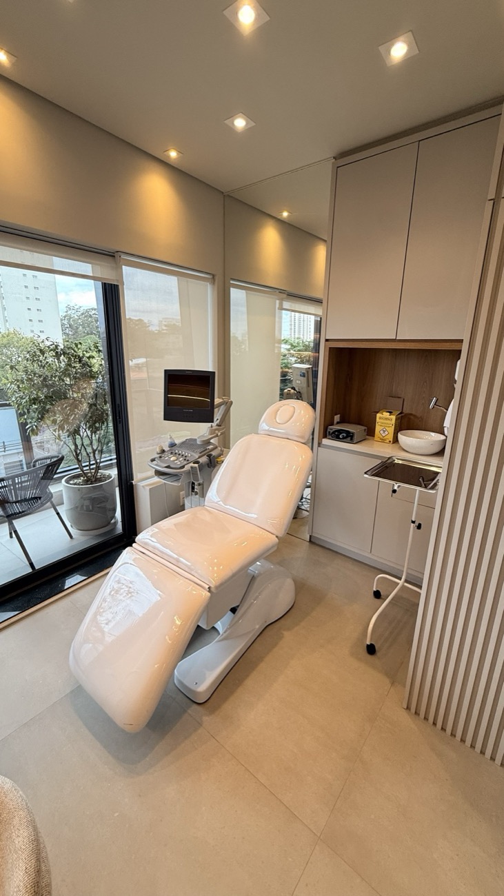 Sala de procedimentos da Clínica UOMO, com poltrona, equipamento e vista para a cidade